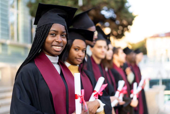 African American young adult women in graduation garments holding a diploma